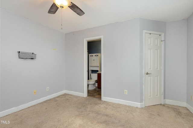 unfurnished bedroom with ensuite bath, carpet flooring, a ceiling fan, and baseboards