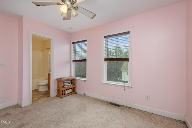 carpeted bedroom with visible vents, baseboards, a ceiling fan, and ensuite bathroom