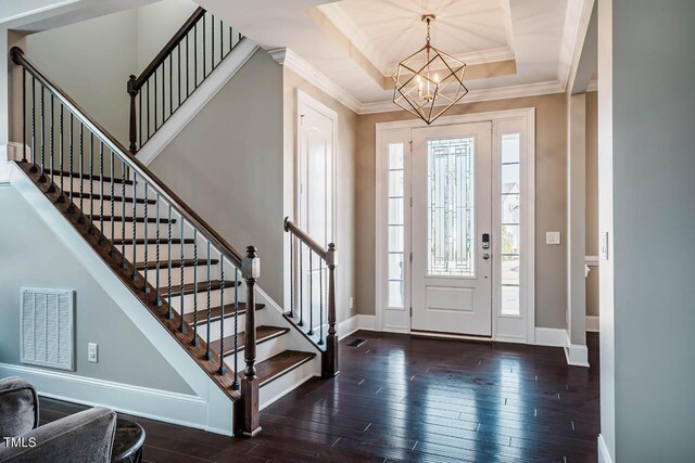 foyer with visible vents, crown molding, baseboards, wood finished floors, and a raised ceiling