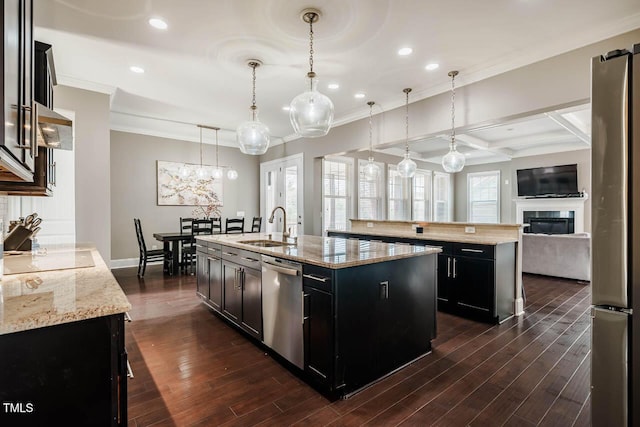 kitchen with a sink, dark cabinetry, appliances with stainless steel finishes, a large island with sink, and dark wood-style flooring