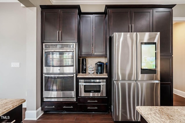 kitchen featuring dark wood finished floors, light stone counters, dark brown cabinets, and stainless steel appliances