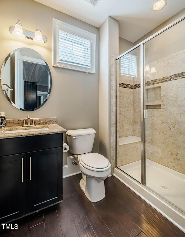 full bath featuring toilet, wood finished floors, a shower stall, baseboards, and vanity