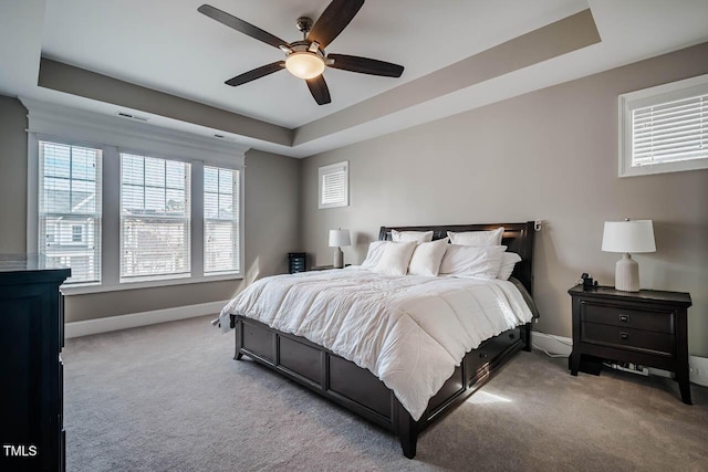 bedroom featuring a tray ceiling, baseboards, and carpet flooring