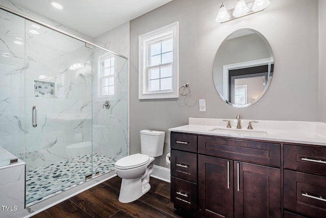 full bath with a marble finish shower, toilet, wood finished floors, and vanity