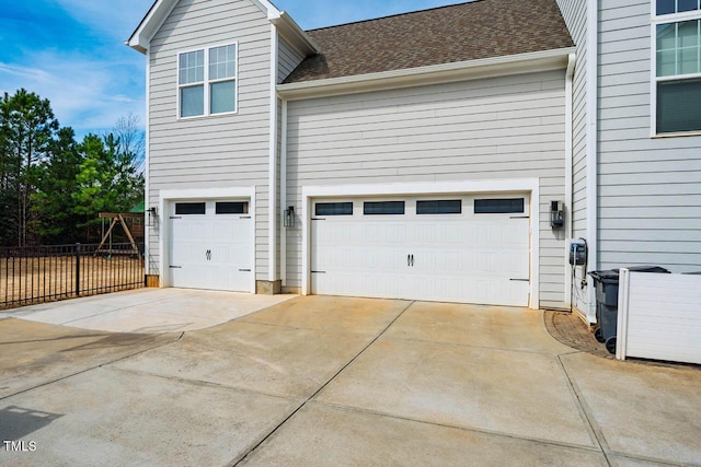 garage featuring concrete driveway and fence