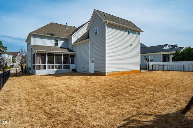 back of house featuring a lawn, a fenced backyard, and a sunroom