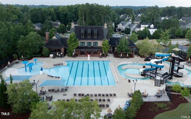 pool featuring a patio area, fence, a water slide, and a hot tub