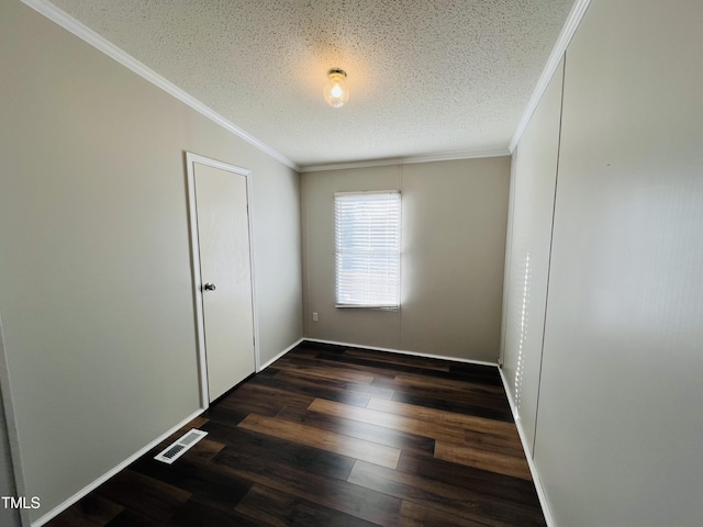 spare room with baseboards, visible vents, dark wood-type flooring, a textured ceiling, and crown molding