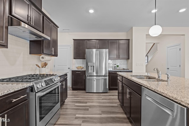 kitchen with dark brown cabinetry, under cabinet range hood, stainless steel appliances, and a sink