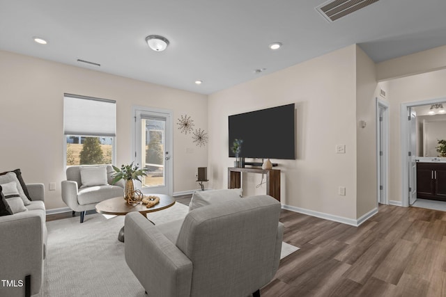 living room featuring recessed lighting, visible vents, baseboards, and wood finished floors