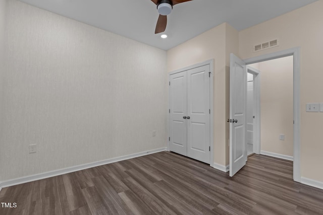 unfurnished bedroom with a closet, visible vents, dark wood-type flooring, ceiling fan, and baseboards