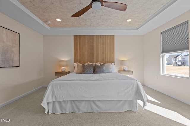 bedroom with carpet floors, baseboards, and a tray ceiling