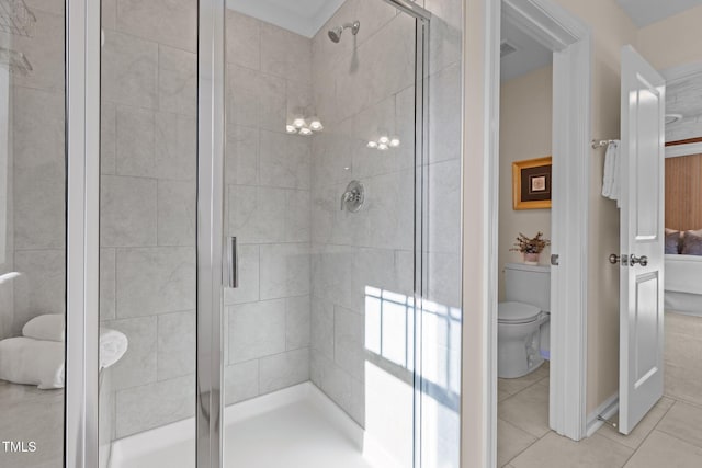 bathroom featuring a stall shower, toilet, and tile patterned floors