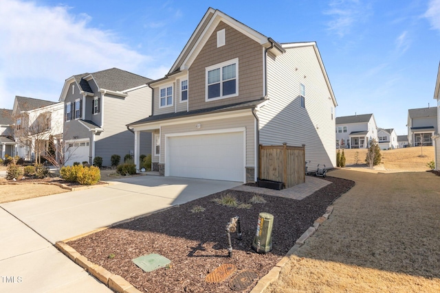 view of front of house featuring driveway, stone siding, an attached garage, and a residential view