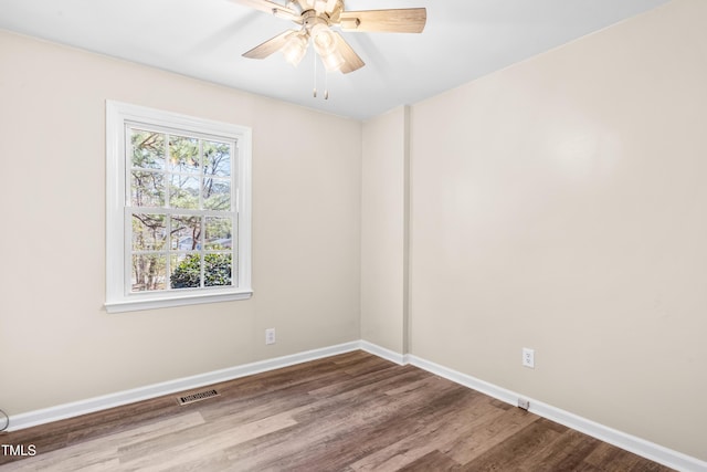 empty room featuring wood finished floors, visible vents, baseboards, and ceiling fan