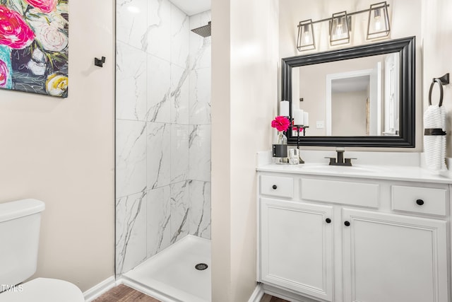 full bathroom featuring vanity, toilet, baseboards, and a marble finish shower