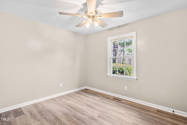 unfurnished room with a ceiling fan, wood finished floors, baseboards, and visible vents