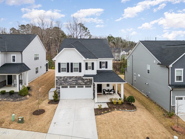 traditional home with a porch, an attached garage, a shingled roof, concrete driveway, and stone siding