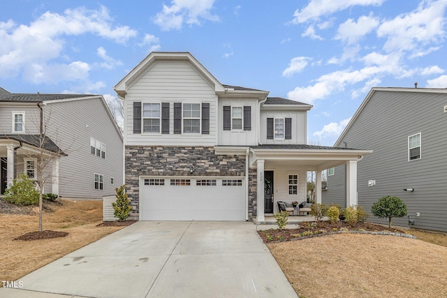 traditional home with a garage, concrete driveway, stone siding, covered porch, and board and batten siding