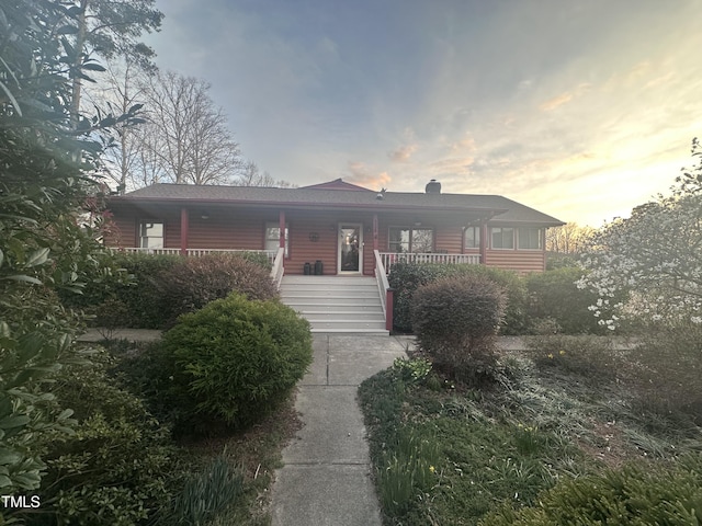 single story home featuring a porch and a chimney