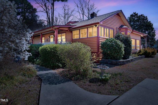 view of side of property featuring a chimney and log veneer siding