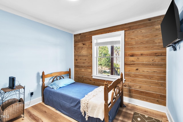 bedroom with wood walls, baseboards, and wood finished floors