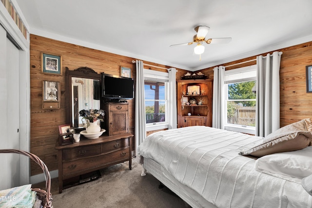 bedroom with a closet, carpet, wood walls, and a ceiling fan