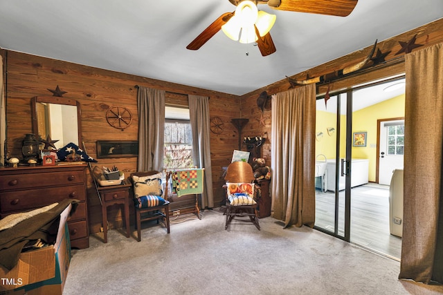 living area featuring wooden walls, a ceiling fan, carpet flooring, and vaulted ceiling