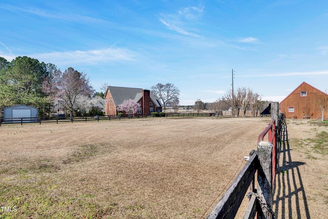 view of yard with a rural view, an outdoor structure, and fence