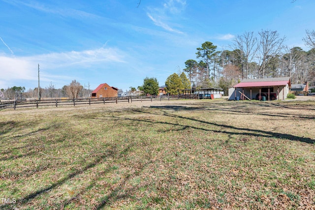 view of yard with a rural view, an outdoor structure, and fence