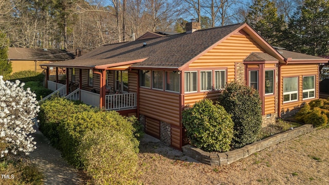 view of property exterior with a chimney, a sunroom, log veneer siding, and roof with shingles