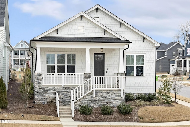 view of front facade featuring covered porch and a shingled roof