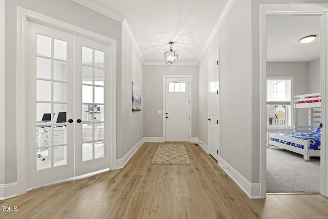 entryway with light wood-style flooring, ornamental molding, baseboards, and french doors