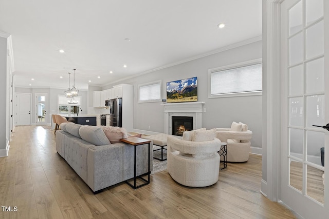 living room with light wood-style floors, ornamental molding, baseboards, and a premium fireplace