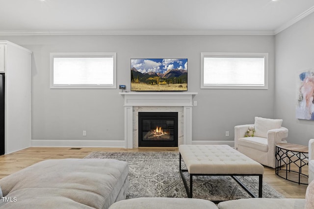 living room featuring light wood-type flooring, baseboards, a fireplace, and ornamental molding