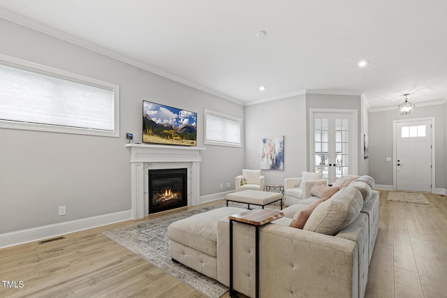 living area featuring ornamental molding, visible vents, light wood-style flooring, and baseboards