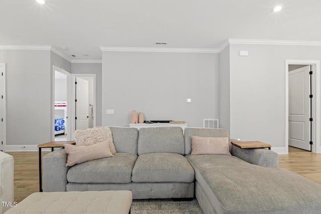 living room featuring baseboards, light wood-style flooring, and crown molding