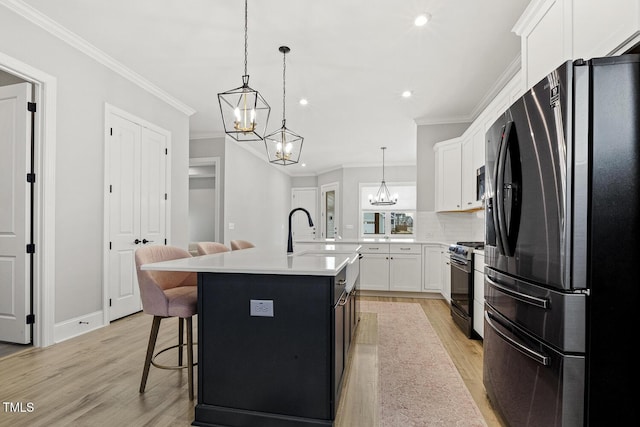 kitchen with light countertops, light wood-style flooring, appliances with stainless steel finishes, white cabinets, and a sink