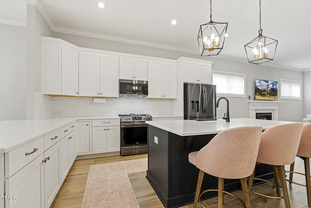 kitchen featuring stainless steel appliances, light countertops, light wood-style flooring, ornamental molding, and a high end fireplace