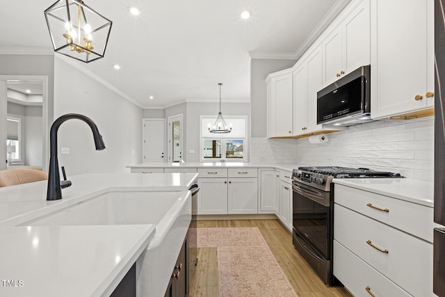 kitchen with stainless steel microwave, an inviting chandelier, light wood-type flooring, a sink, and gas stove