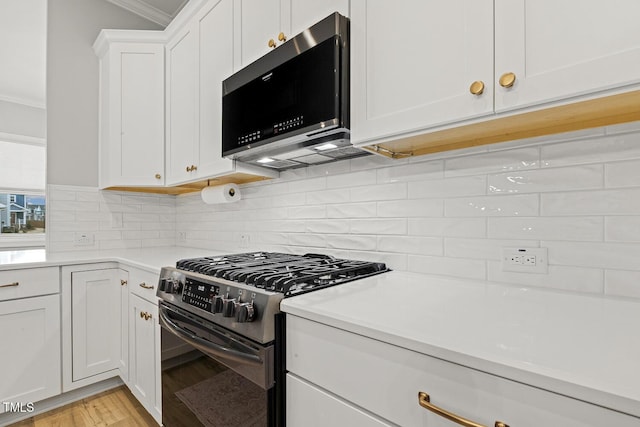 kitchen featuring backsplash, white cabinetry, stainless steel appliances, and crown molding