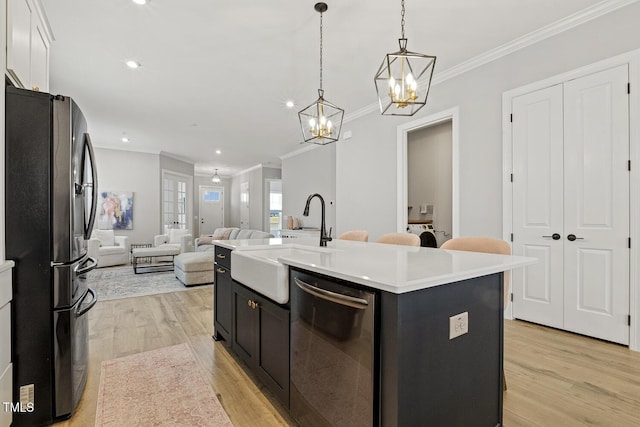 kitchen with a sink, light countertops, freestanding refrigerator, dishwasher, and light wood finished floors