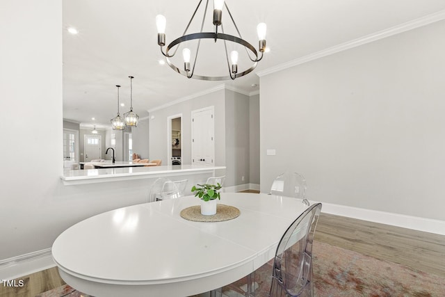 dining space featuring baseboards, ornamental molding, wood finished floors, and a notable chandelier