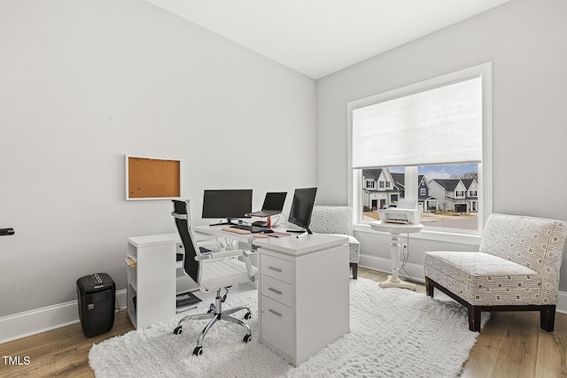 home office with light wood-style flooring and baseboards