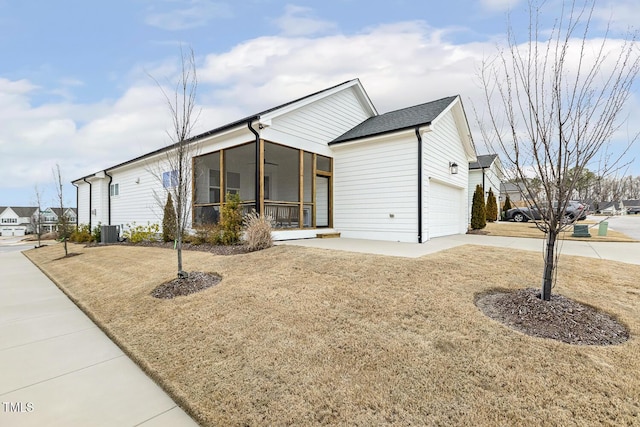 view of front of property featuring driveway, an attached garage, cooling unit, and a sunroom