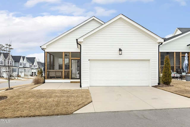 view of front of home with a garage, a residential view, a sunroom, and concrete driveway