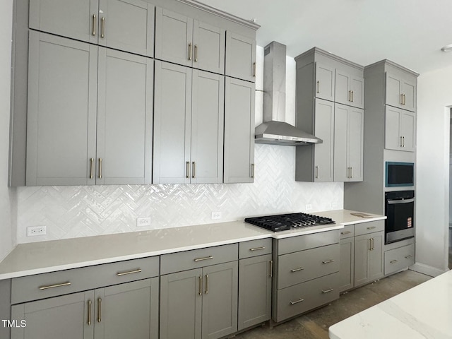 63 Daybreak Way, Fuquay Varina, NC 27526 - kitchen featuring appliances with stainless steel finishes, wall chimney exhaust hood, gray cabinets, dark wood-type flooring, and tasteful backsplash