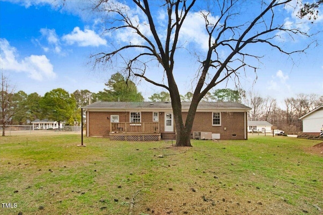 back of property with a deck, brick siding, crawl space, and a lawn