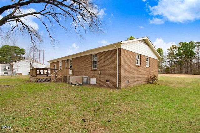 back of property featuring crawl space, brick siding, a lawn, and a wooden deck