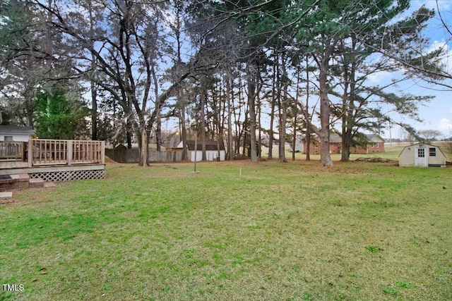 view of yard with a storage shed, an outdoor structure, a wooden deck, and fence